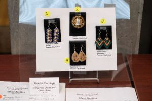 Four pairs of beaded moosehide earrings on a display board.