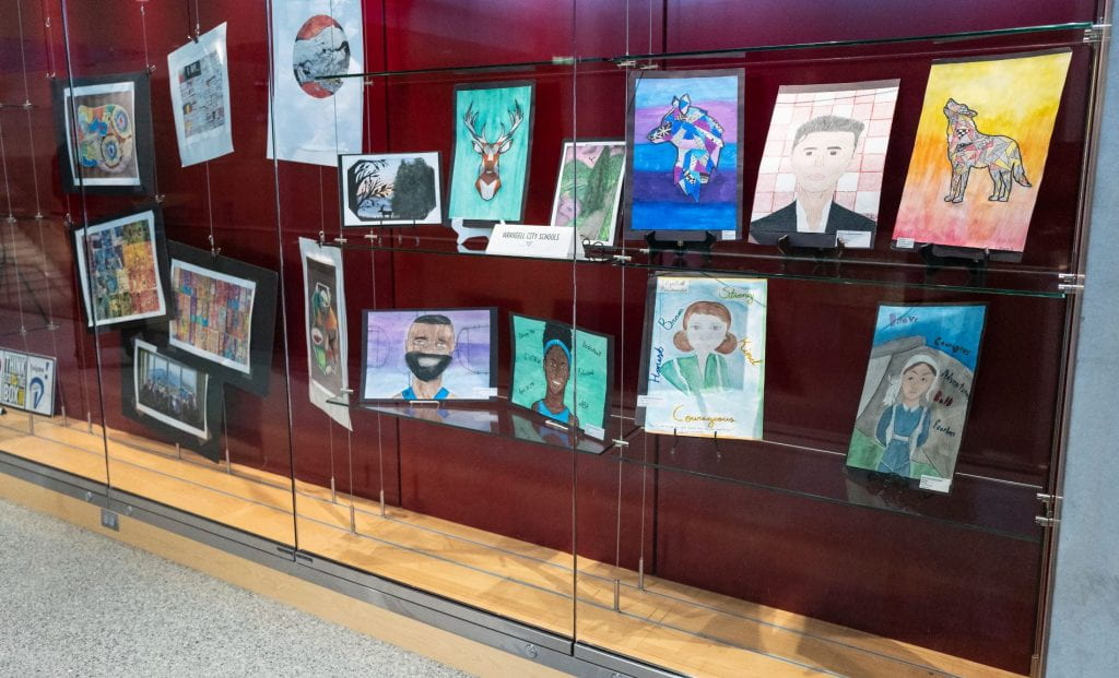 A glass cases at the museum with a variety of student art pieces. 