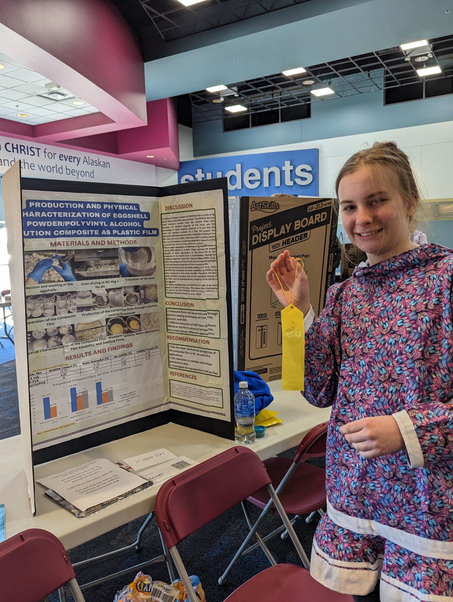 A student standing in front of the board for her science project.